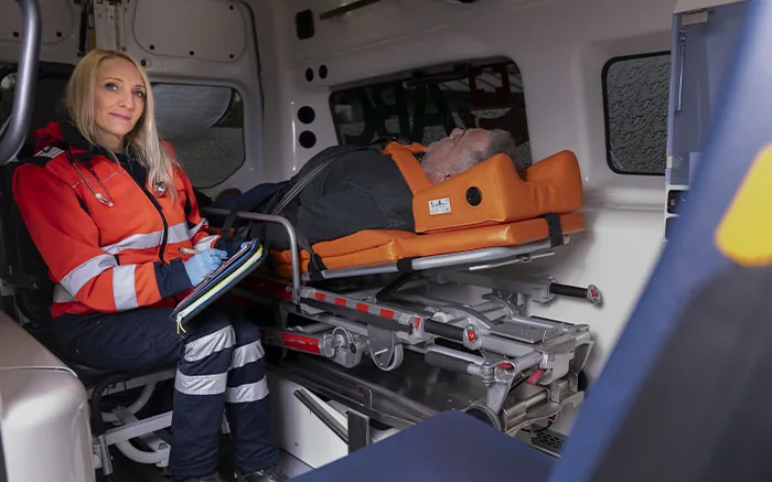 Rettungssanitäterin begleitet einen liegenden Patienten im Krankentransportwagen der ABC Ambulanz